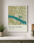 Location Map — Tower of London: "A white-framed location map print on a shelf, showing a sage green and cream street map of the Tower of London with the River Thames running through it — styled with a potted plant, a wooden chopping board, and a stoneware jug