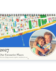 A spiral-bound 2027 personallised calendar titled 'Our Favourite Places' with a colourful coastal map illustration, a blue and white design, and a circular inset photo of two children hugging on a beach.