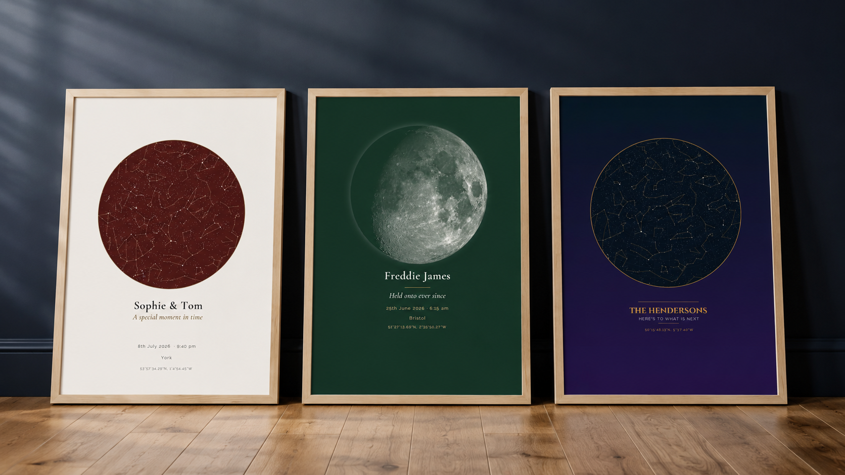 Three framed sky map prints leaning against a wall — a burgundy star map, a green moon phase print, and a navy star map, each personalised with a name, date, and location